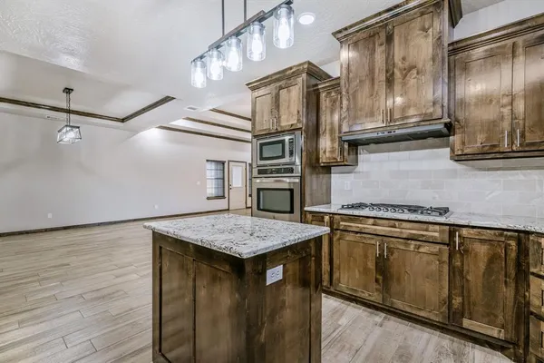 a kitchen with stainless steel appliances granite countertop a sink and wooden cabinets