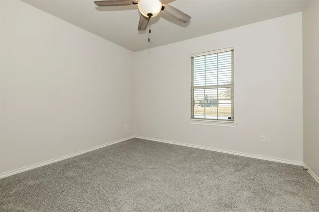 an empty room with a window and a ceiling fan