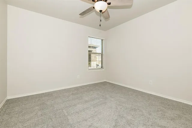 an empty room with a chandelier fan and windows