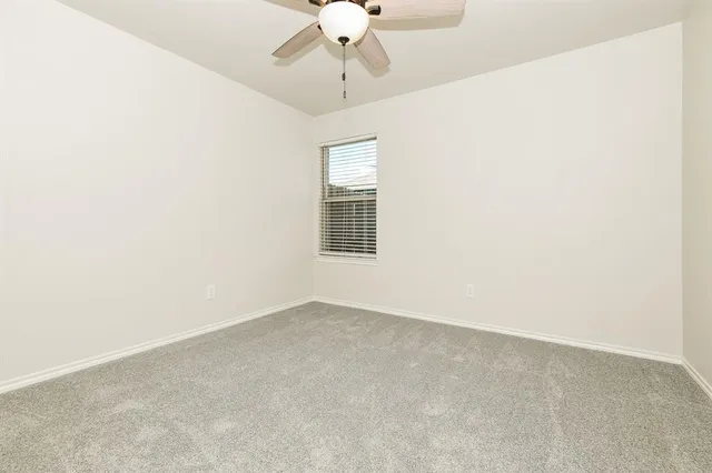 an empty room with a chandelier fan and windows