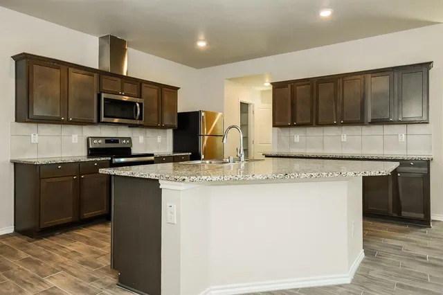 a kitchen with stainless steel appliances granite countertop a stove top oven a sink a microwave and a refrigerator