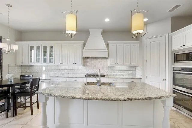 a kitchen with stainless steel appliances granite countertop a sink a stove and a wooden cabinets