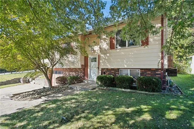 a view of a yard in front of a house with large tree
