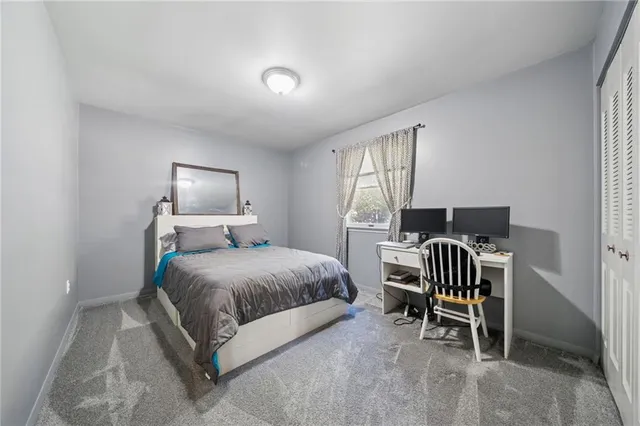 a bedroom with a bed chair and two windows