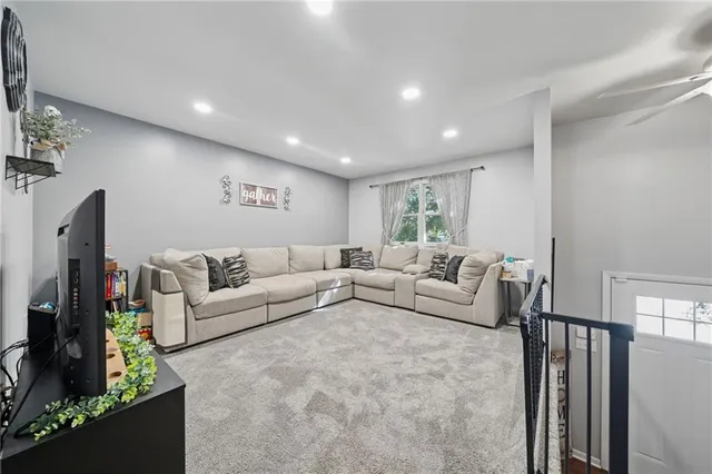 a living room with furniture a flat screen tv and a window