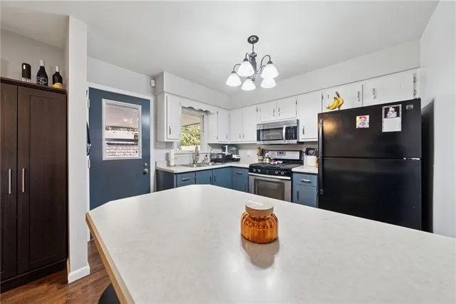 a kitchen with stainless steel appliances granite countertop a refrigerator a stove a sink dishwasher and a refrigerator with wooden floor