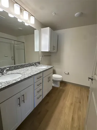 a bathroom with a granite countertop sink a toilet and a mirror