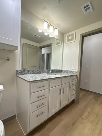 a bathroom with a granite countertop sink and a large mirror