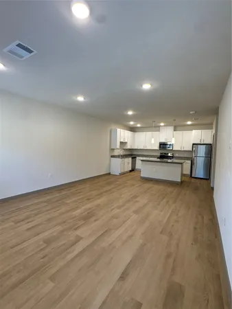 a kitchen with stainless steel appliances granite countertop a stove top oven a sink dishwasher and white cabinets with wooden floor