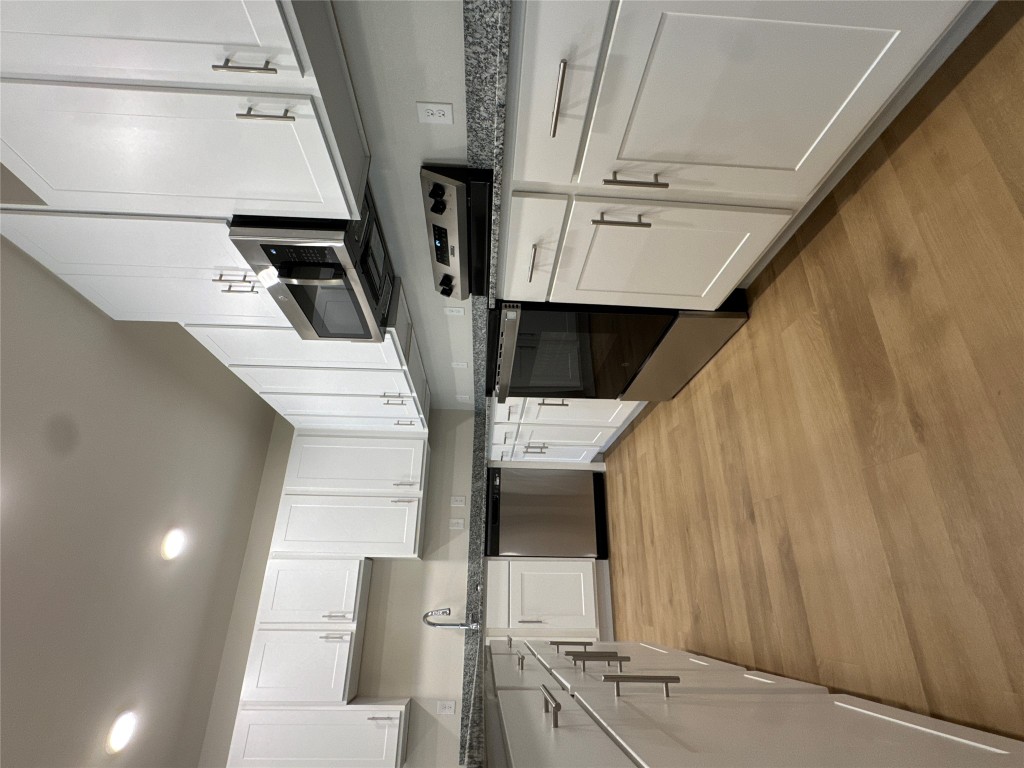 691 Union Chapel Road, Unit C1 Cedar Creek, TX 78612 - Photo 23 of 35 Kitchen featuring appliances with stainless steel finishes, white cabinetry, light wood-type flooring, dark stone countertops, and recessed lighting