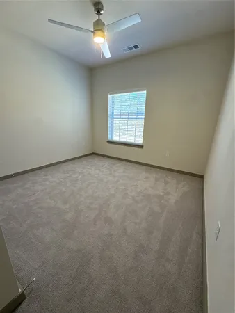 an empty room with windows and ceiling fan
