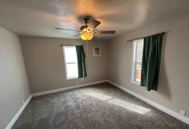 a view of an empty room with a chandelier fan