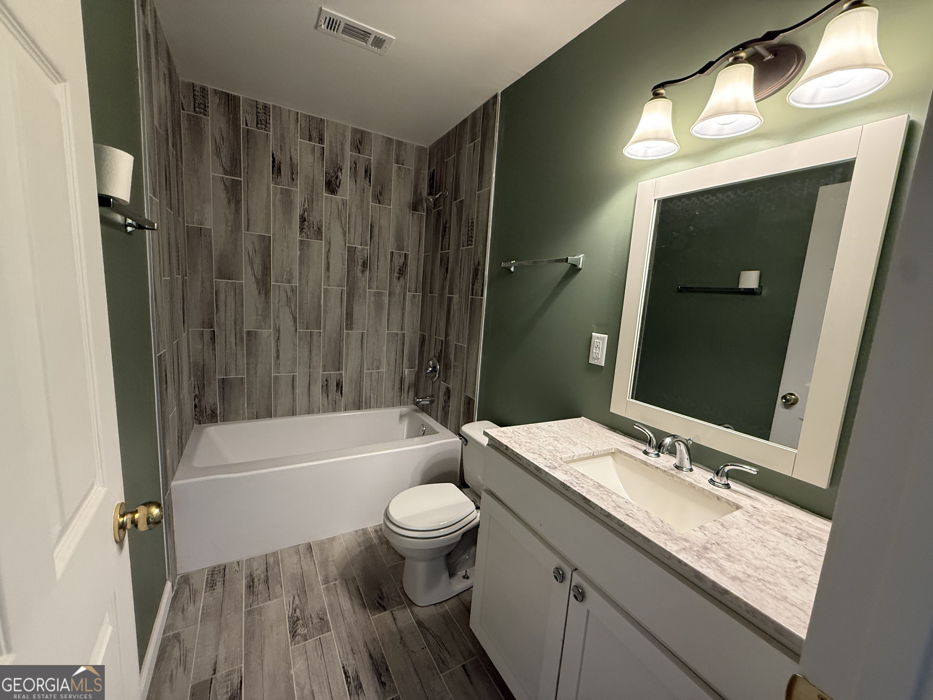 240 Sims Street Barnesville, GA 30204 - Photo 21 of 25 a bathroom with a granite countertop sink toilet a large mirror a bathtub and shower