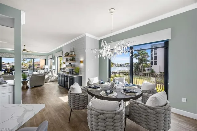 a view of a dining room and livingroom with furniture wooden floor a chandelier