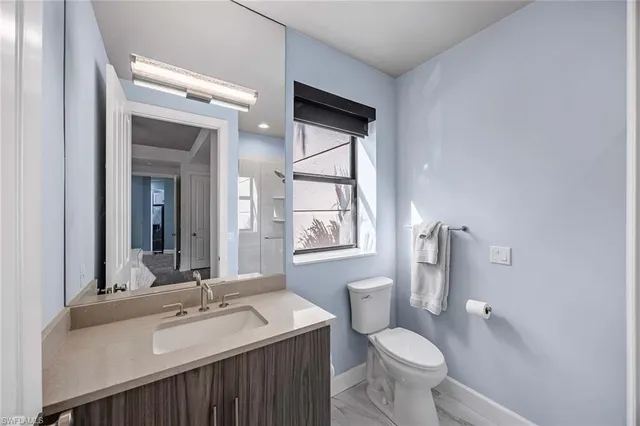 a bathroom with a granite countertop toilet sink and mirror