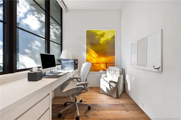 a room with lots of white furniture and a wooden floor