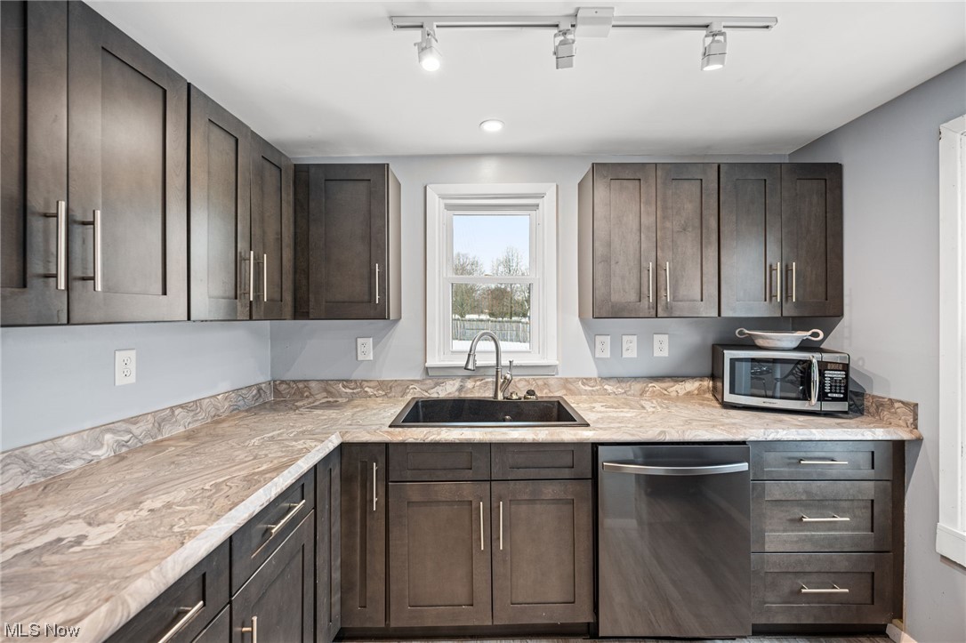 2986 Worrell Road Willoughby, OH 44094 - Photo 11 of 36 Kitchen featuring dark brown cabinetry, rail lighting, sink, and stainless steel appliances