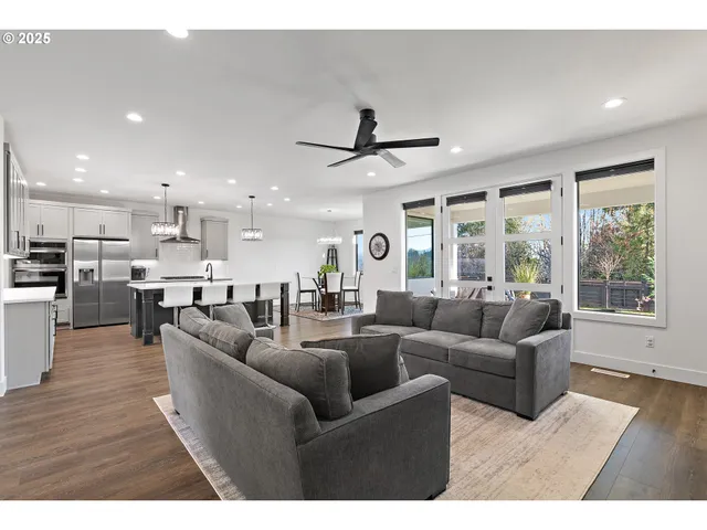 a living room with furniture kitchen area and a large window