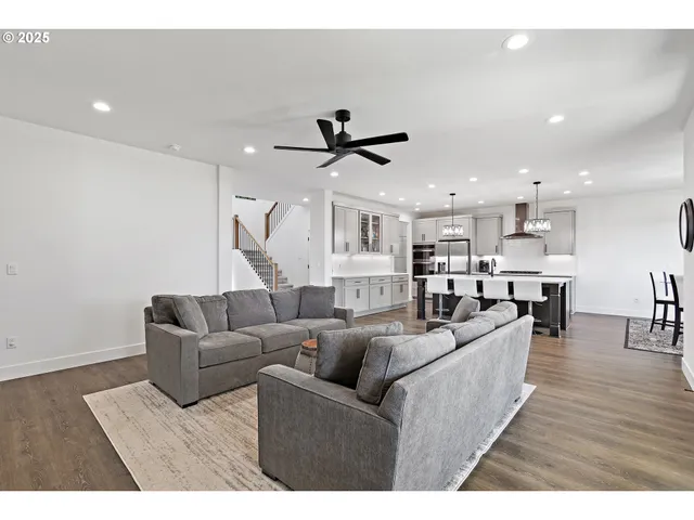 a living room with furniture kitchen view and a wooden floor