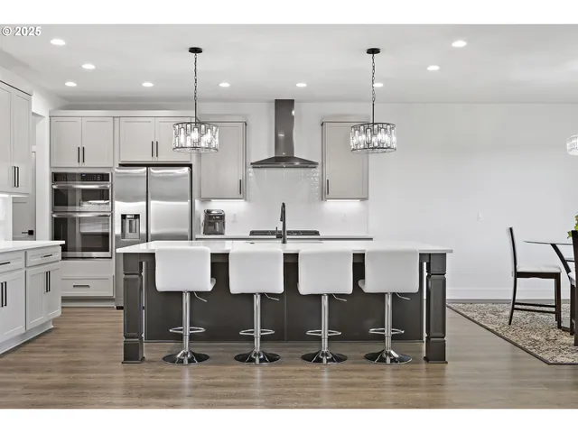 a kitchen with kitchen island granite countertop a dining table chairs and white cabinets
