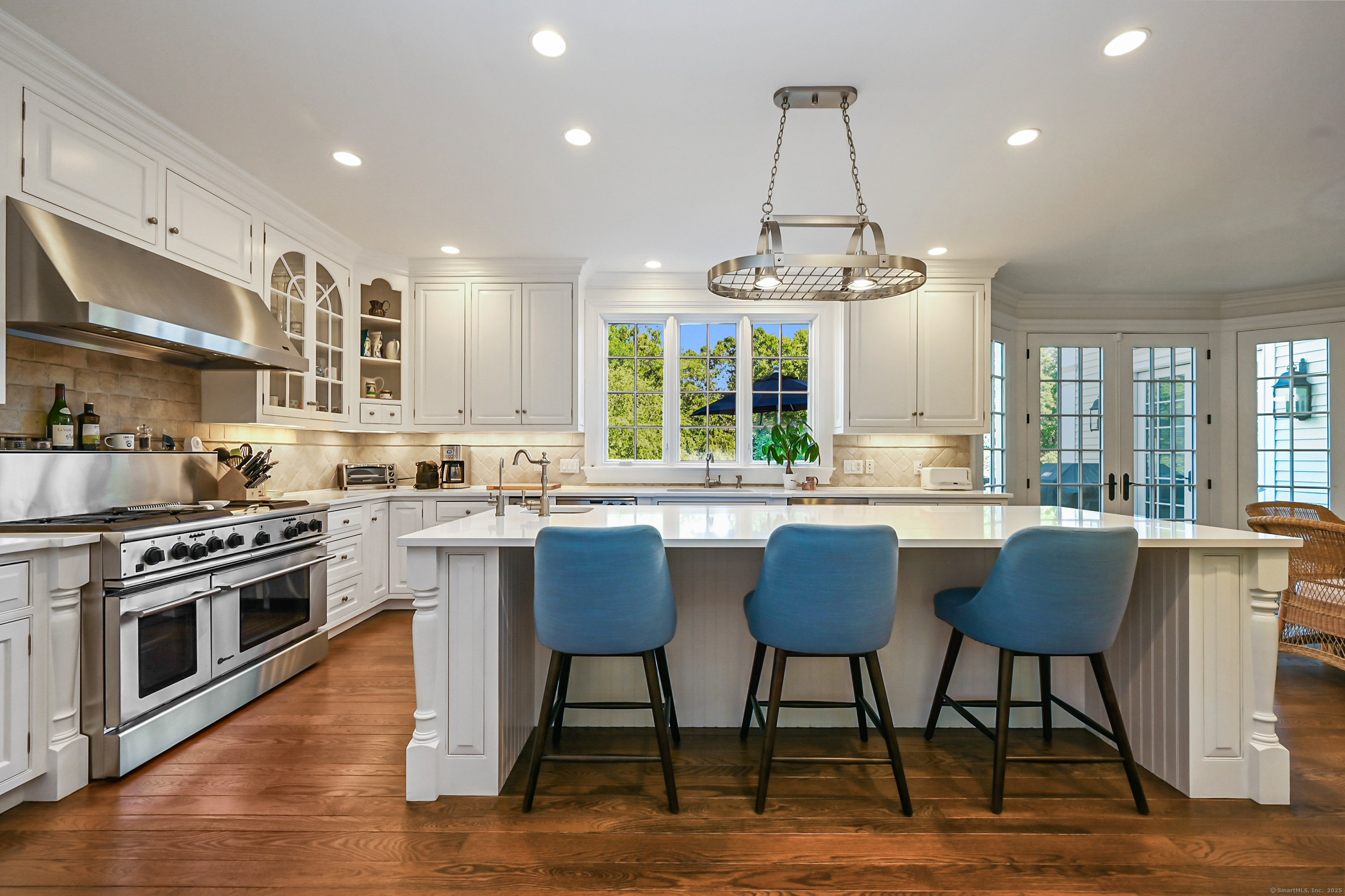 1084 Sturges Highway Fairfield, CT 06880 - Photo 9 of 40 a kitchen with stainless steel appliances granite countertop a stove top oven a sink dishwasher a dining table and chairs with wooden floor