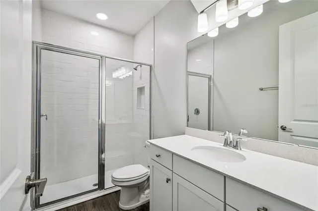 a large kitchen with kitchen island a stove a sink a refrigerator and white cabinets with wooden floor