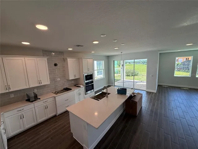 a kitchen with kitchen island a stove a wooden floor and white cabinets
