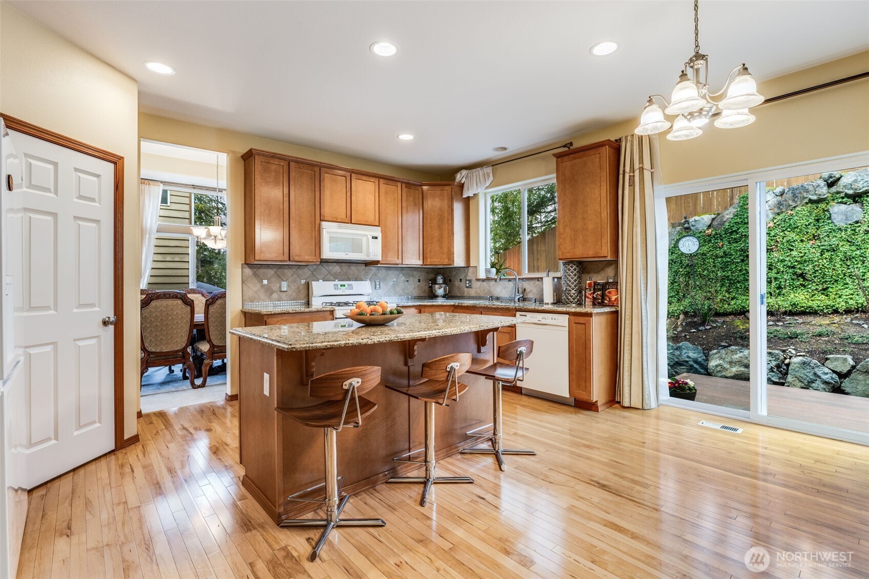 18615 13th Drive Southeast Bothell, WA 98012 - Photo 8 of 38 a open kitchen with stainless steel appliances granite countertop a stove top oven a refrigerator a dining table and chairs with wooden floor