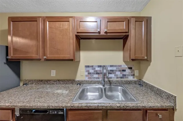 a kitchen with granite countertop a sink a stove and cabinets