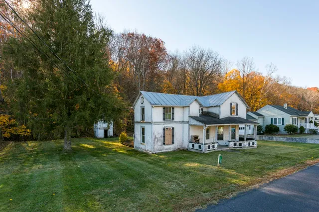 a front view of a house with a yard and large tree