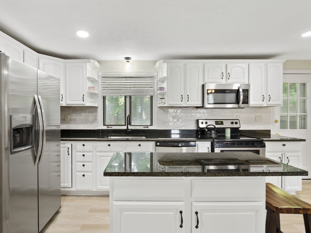 13 Plain Street Upton, MA 01568 - Photo 11 of 42 a kitchen with stainless steel appliances granite countertop a sink a stove a refrigerator a center island and cabinets