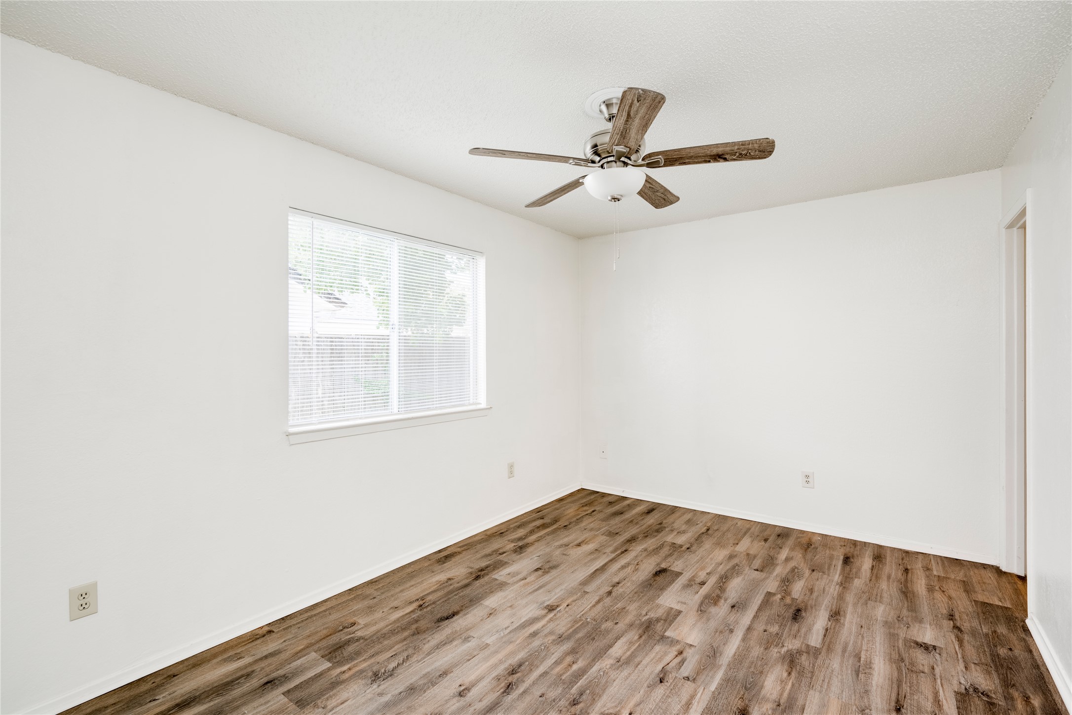 7918 West Gate Boulevard Austin, TX 78745 - Photo 11 of 31 Natural light fills this room with durable wood-look flooring and a functional ceiling fan.