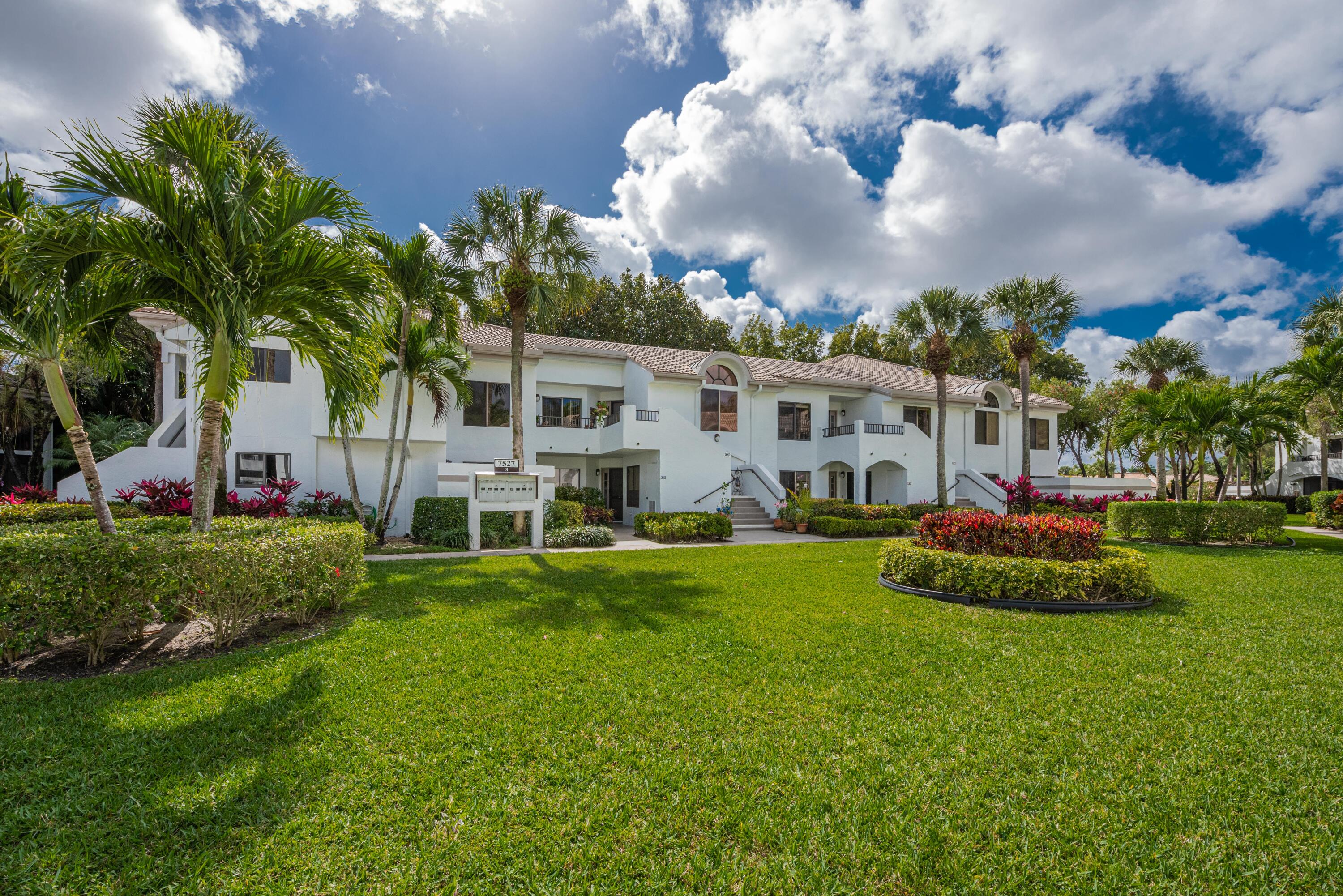 7527 Glendevon Lane, Unit 803 Delray Beach, FL 33446 - Photo 32 of 35 a view of a white house with a big yard and potted plants and big trees