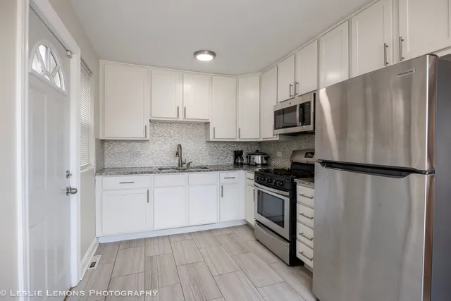 a kitchen with stainless steel appliances granite countertop a refrigerator stove a sink and dishwasher with wooden floor