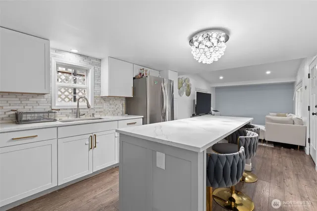 a kitchen with a table chairs a sink dishwasher and a stove with wooden floor