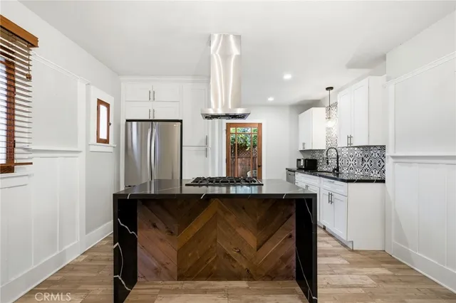 a kitchen with stainless steel appliances kitchen island granite countertop a sink refrigerator and cabinets