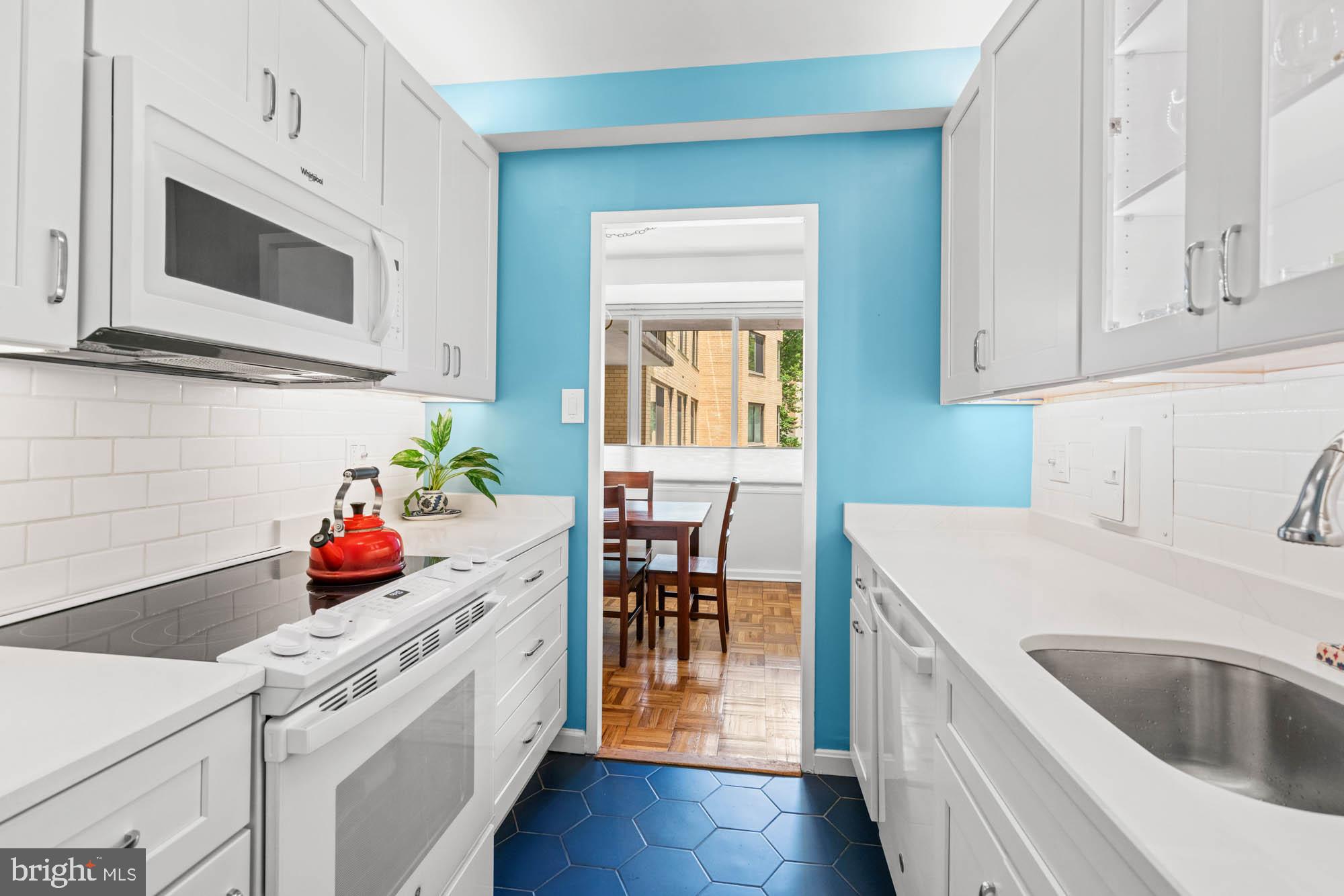 4740 Connecticut Avenue Northwest, Unit 204 Washington, DC 20008 - Photo 16 of 33 a kitchen with stainless steel appliances a white stove top oven a sink dishwasher and white cabinets with wooden floor
