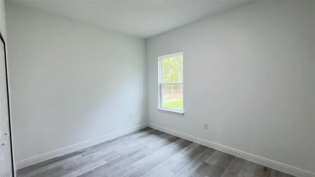 an empty room with a window and wooden floor