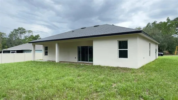 a front view of house with yard and trees in the background