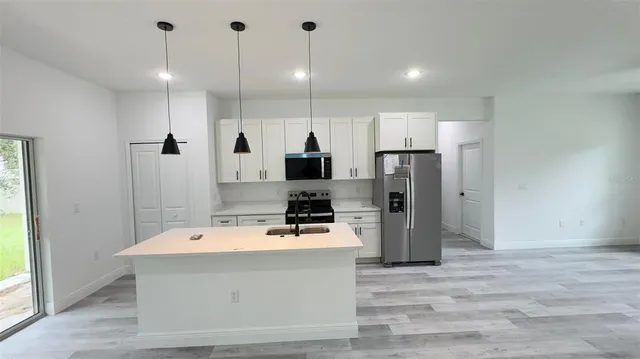 a room with stainless steel appliances kitchen island a refrigerator sink and cabinets