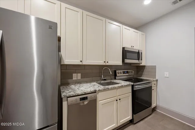 a kitchen with stainless steel appliances granite countertop white cabinets stove a microwave and a refrigerator