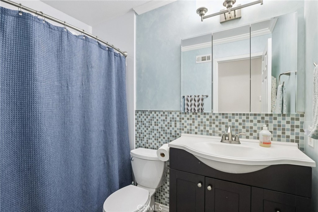27191 Valleymont Road Lake Forest, CA 92630 - Photo 13 of 37 a bathroom with a sink a toilet a mirror and shower curtain