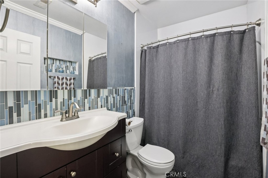 27191 Valleymont Road Lake Forest, CA 92630 - Photo 18 of 37 a bathroom with a sink a toilet a mirror and shower curtain