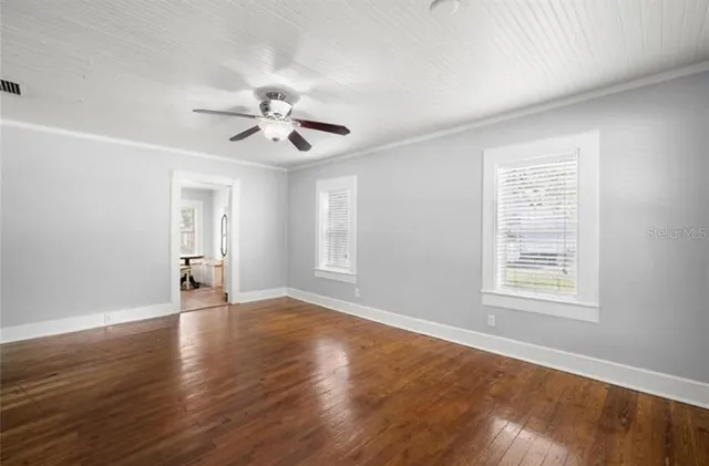 a view of an empty room with window and wooden floor