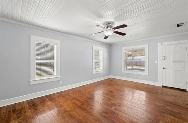 a view of an empty room with a window and wooden floor
