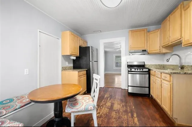 a kitchen with stainless steel appliances a sink a stove a refrigerator cabinets and a dining table