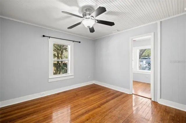 a view of an empty room with wooden floor and a window