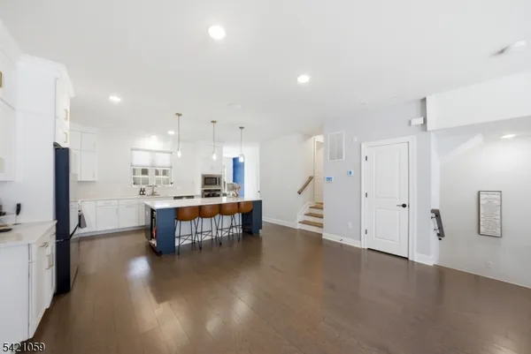 a open kitchen with stainless steel appliances kitchen island hardwood floor and a sink