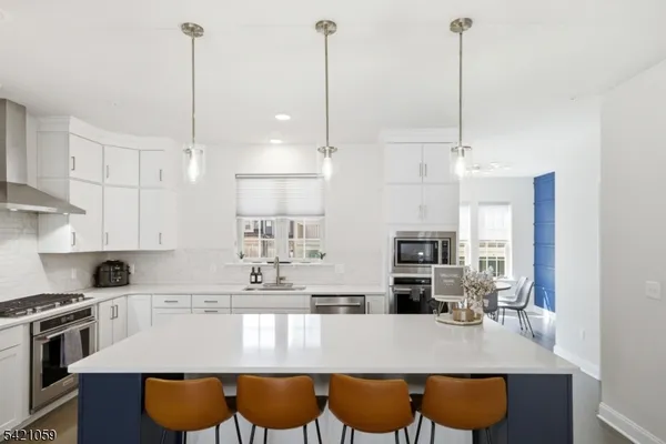 a kitchen with stainless steel appliances granite countertop a stove top oven a sink a counter and chairs