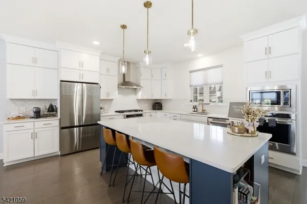 a large kitchen with kitchen island a stove a refrigerator a sink a dining table and chairs with wooden floor